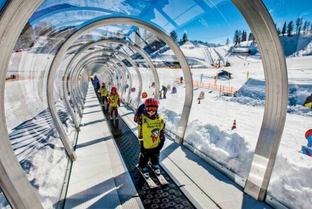 Skilift voor kinderen in een wintersportgebied Kinderen skiën naar beneden in een glazen skilift in een sneeuwlandschap.